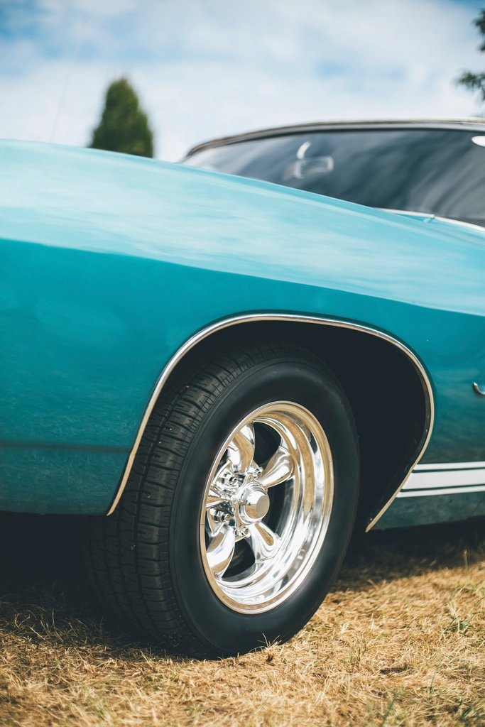 Classic teal muscle car with its front wheel and tire in focus