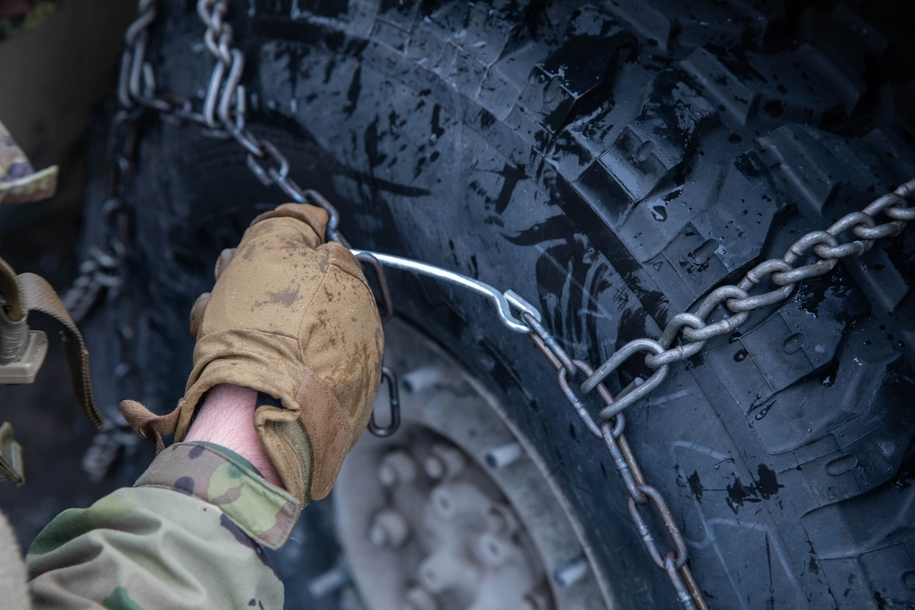 Hands fitting snow chains onto a winter tire